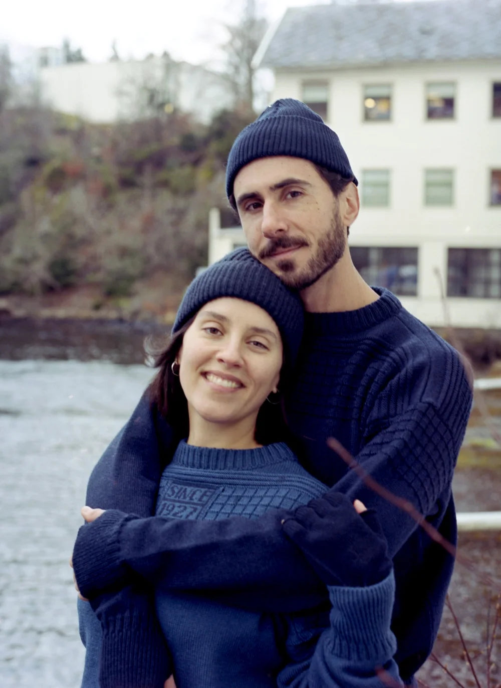 alt
Un hombre y una mujer sonrientes con gorros y suéteres de punto azul marino abrazándose al aire libre junto a un río, mostrando Norlender Knitwear en un entorno acogedor y elegante.