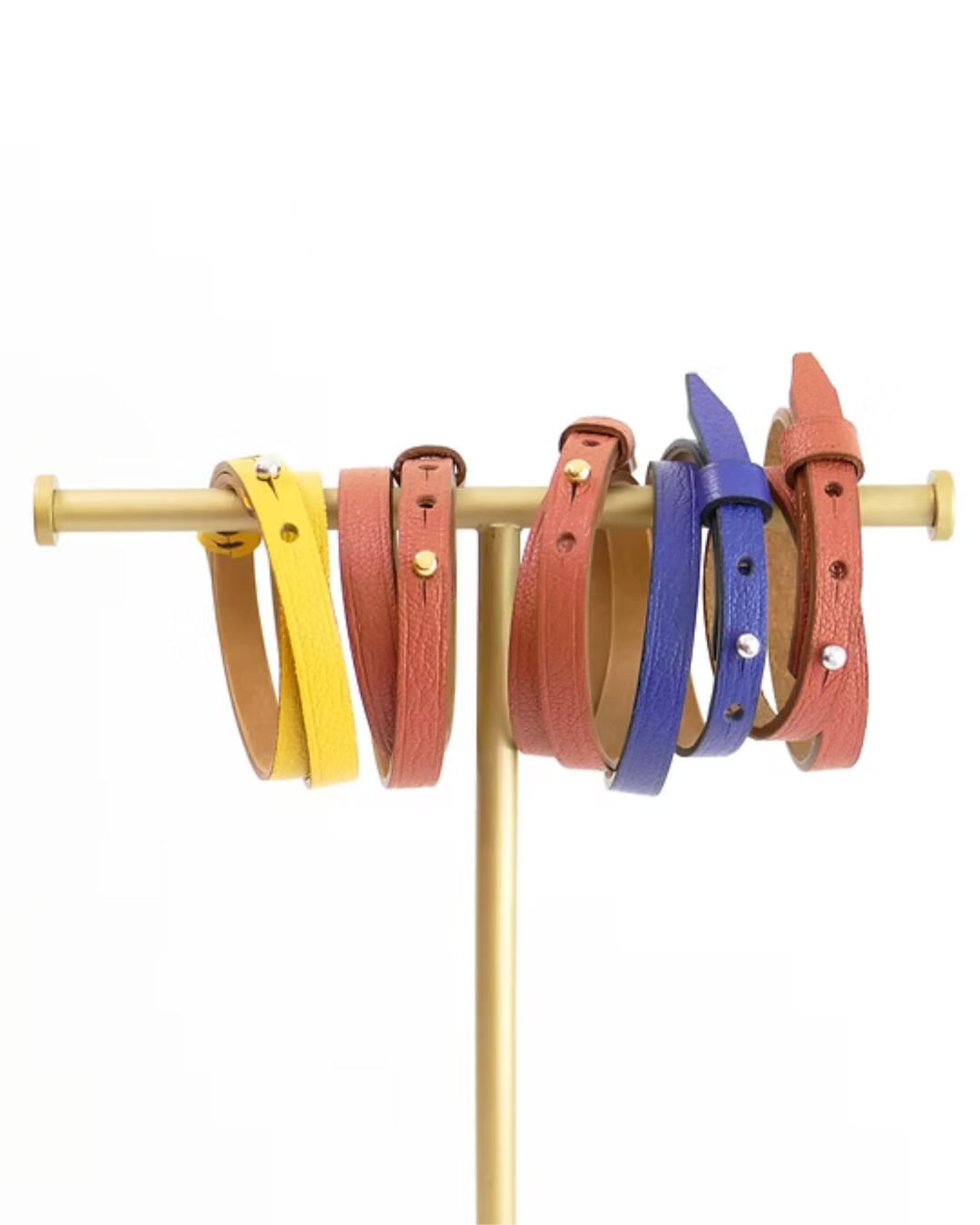 Set of colorful leather bracelets on a stand against a white background