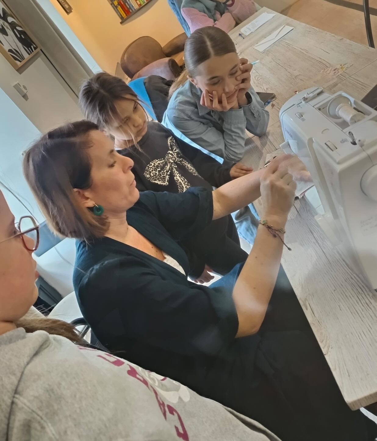 Group of people sitting around a table with electronic devices on a counter.